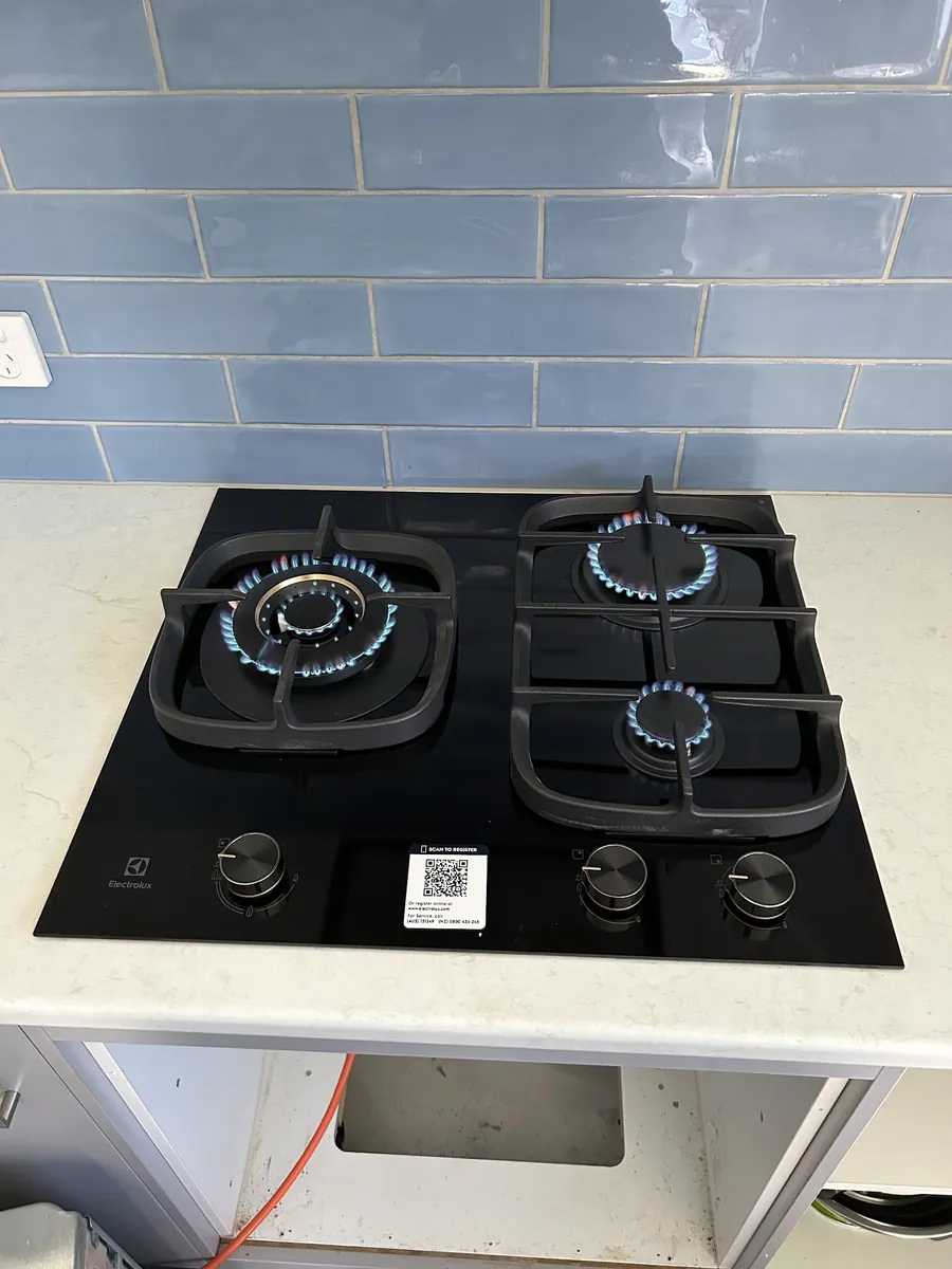 Four burner gas cooktop running with blue flames after installation